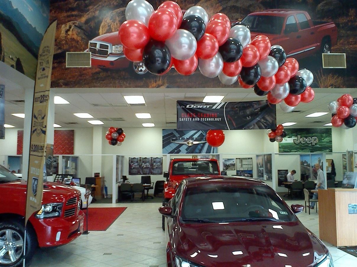 A car dealership with balloons hanging from the ceiling