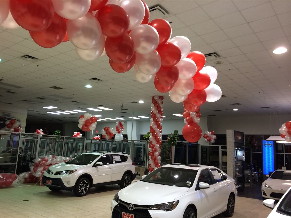 A car dealership is decorated with red and white balloons