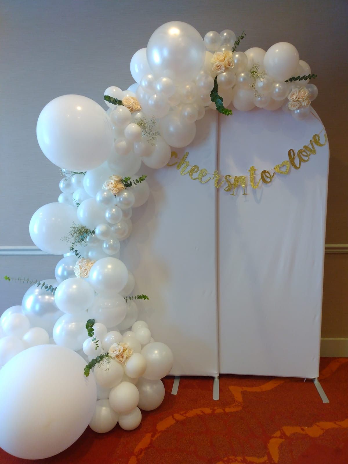 A white wall with white balloons and flowers on it.