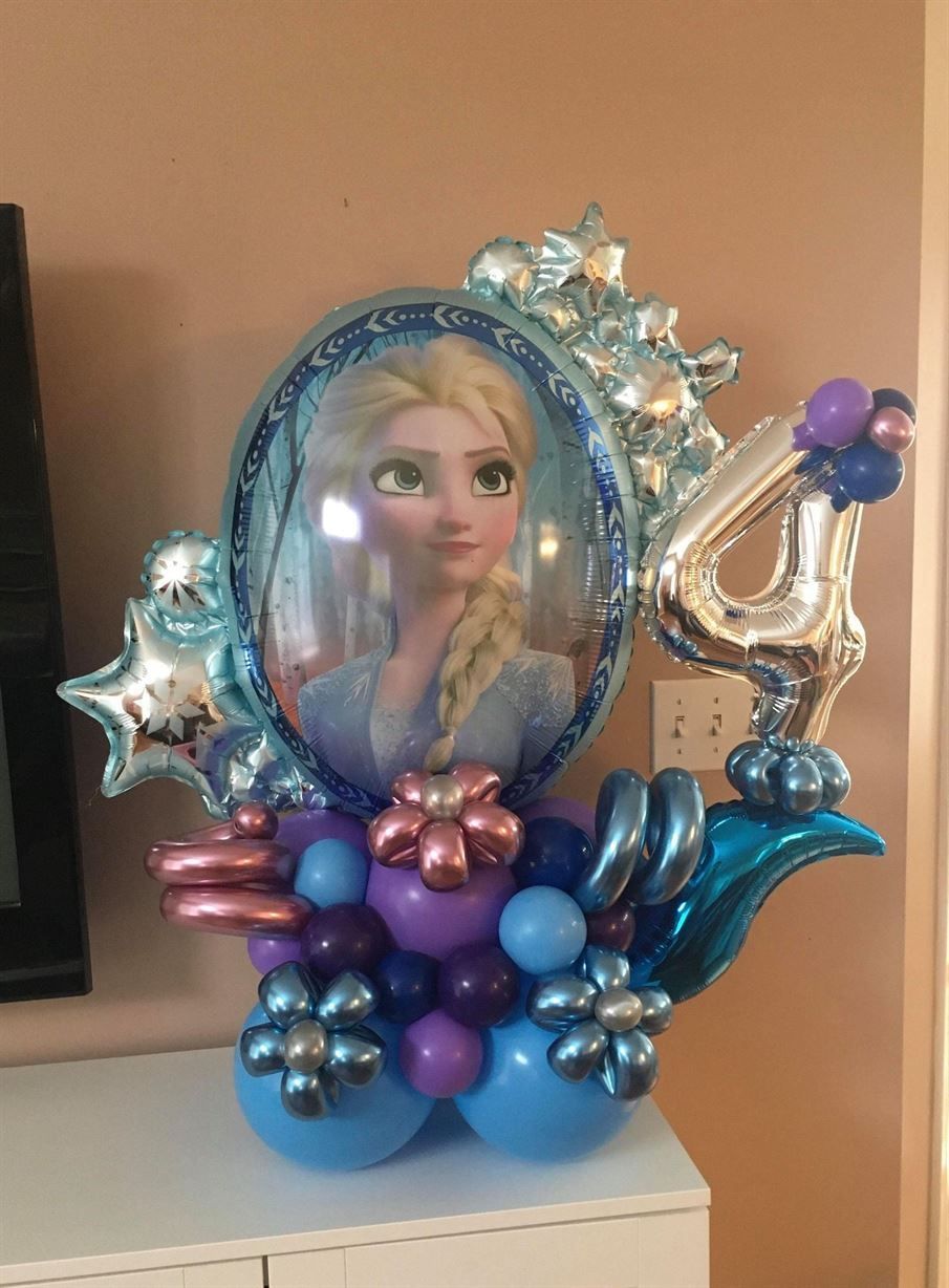 A frozen balloon bouquet with a picture of elsa on it is on a table.