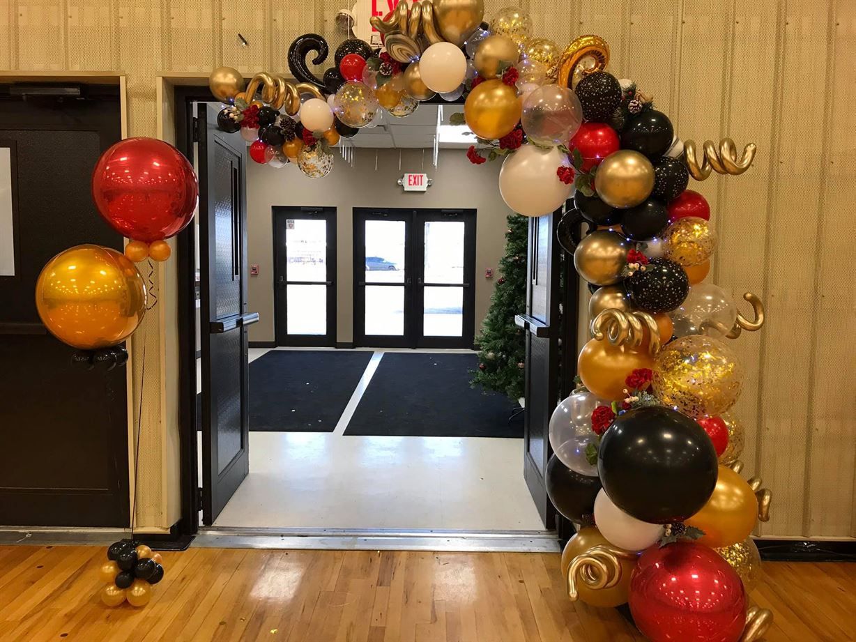 A room decorated with red , gold , and black balloons.