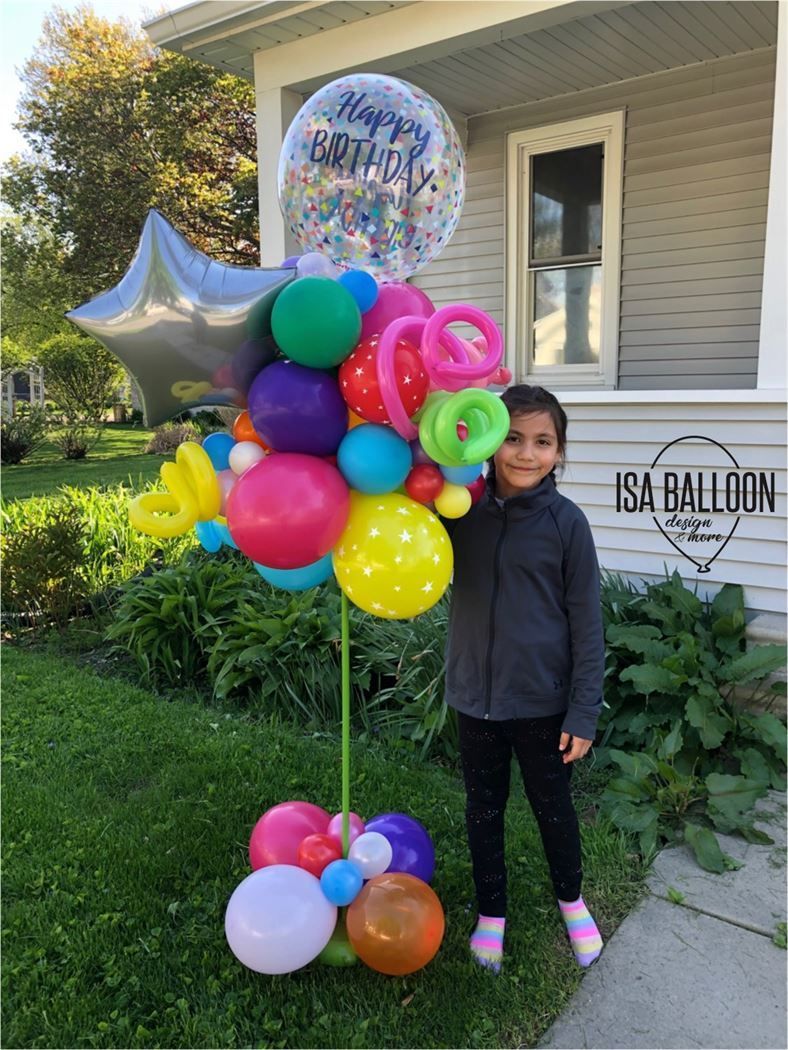 A little girl is holding a bunch of balloons in front of a house.