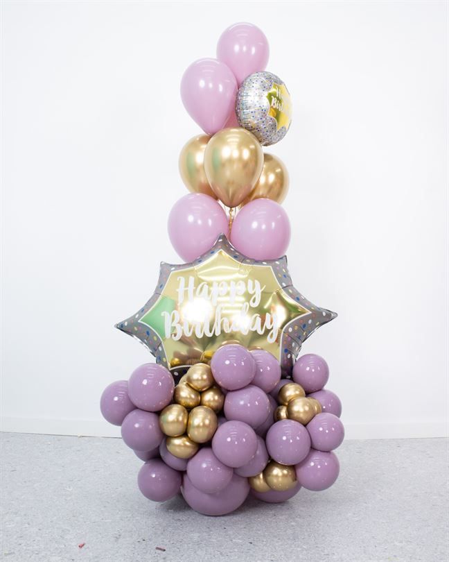 A bunch of purple and gold balloons with a happy birthday balloon
