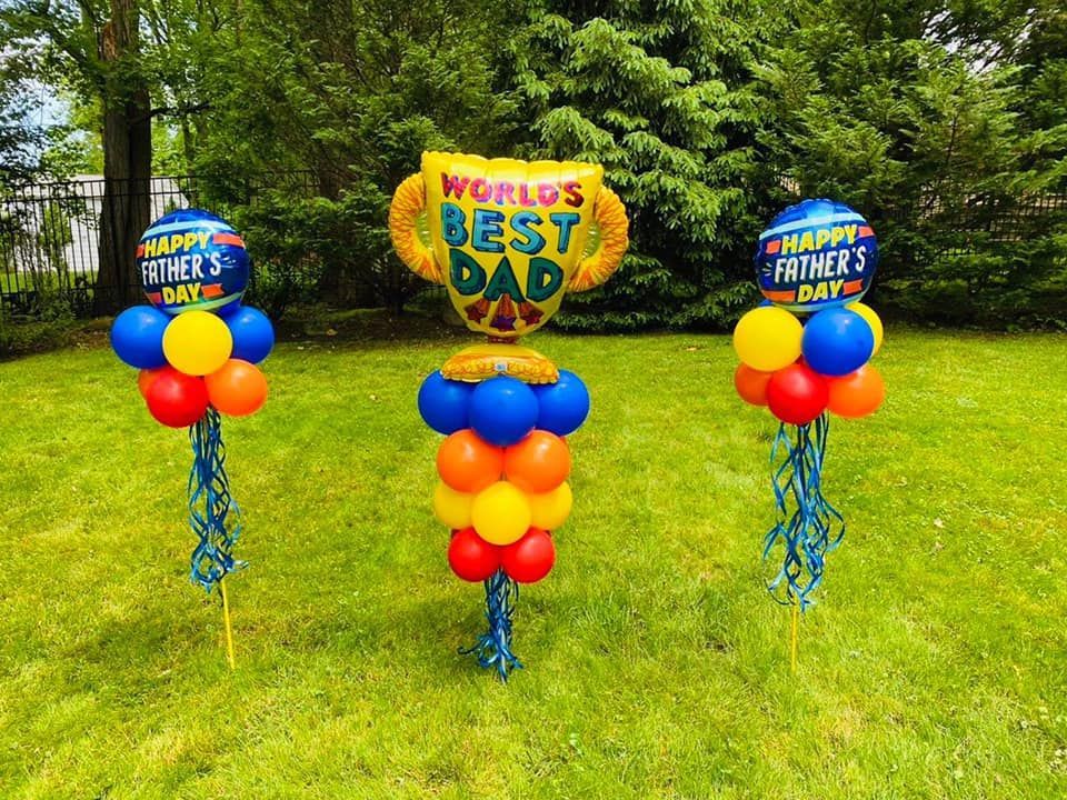 Three balloons are sitting on top of a lush green field.