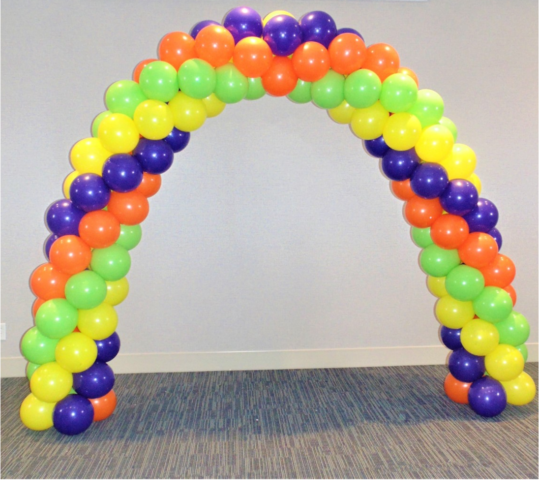 A rainbow colored balloon arch is sitting on the floor