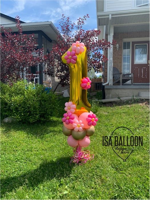 A number one balloon is sitting in the grass in front of a house.