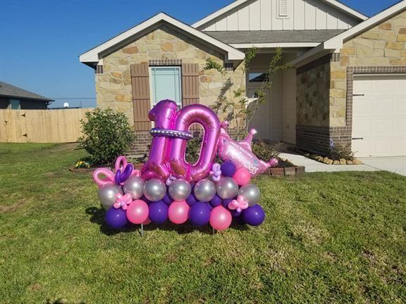 A bunch of balloons are sitting in front of a house.