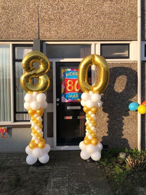 A house with balloons in front of it that say 80