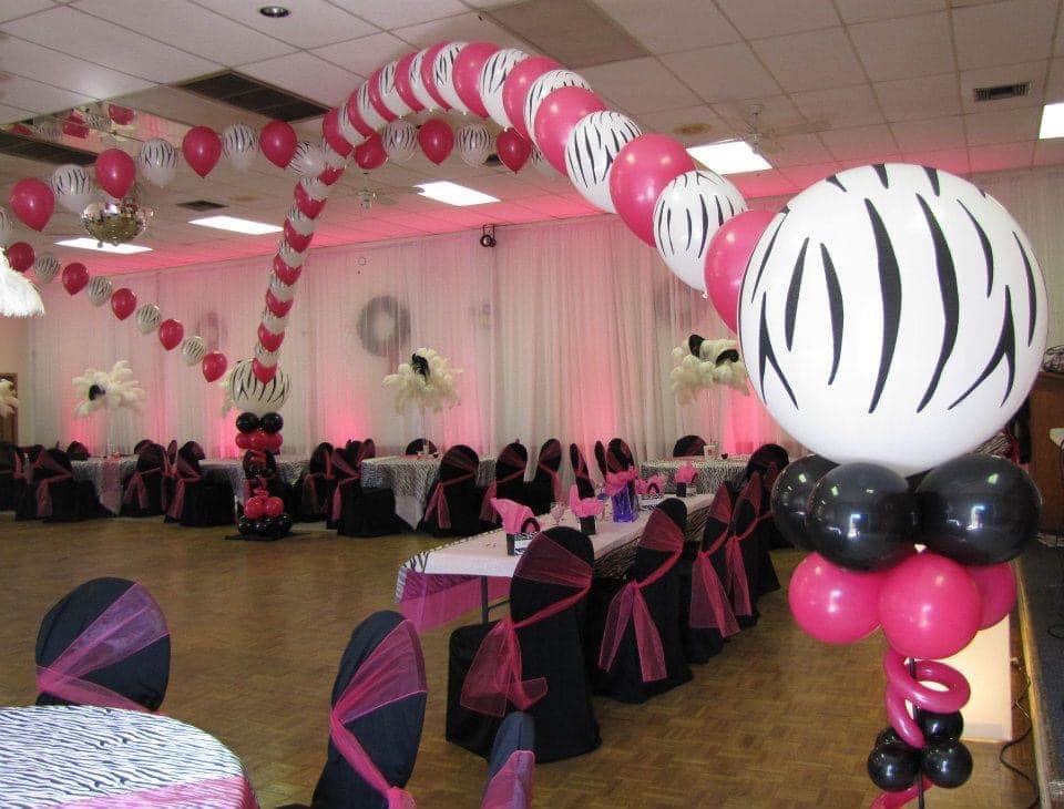 A room with tables and chairs decorated with pink and black balloons