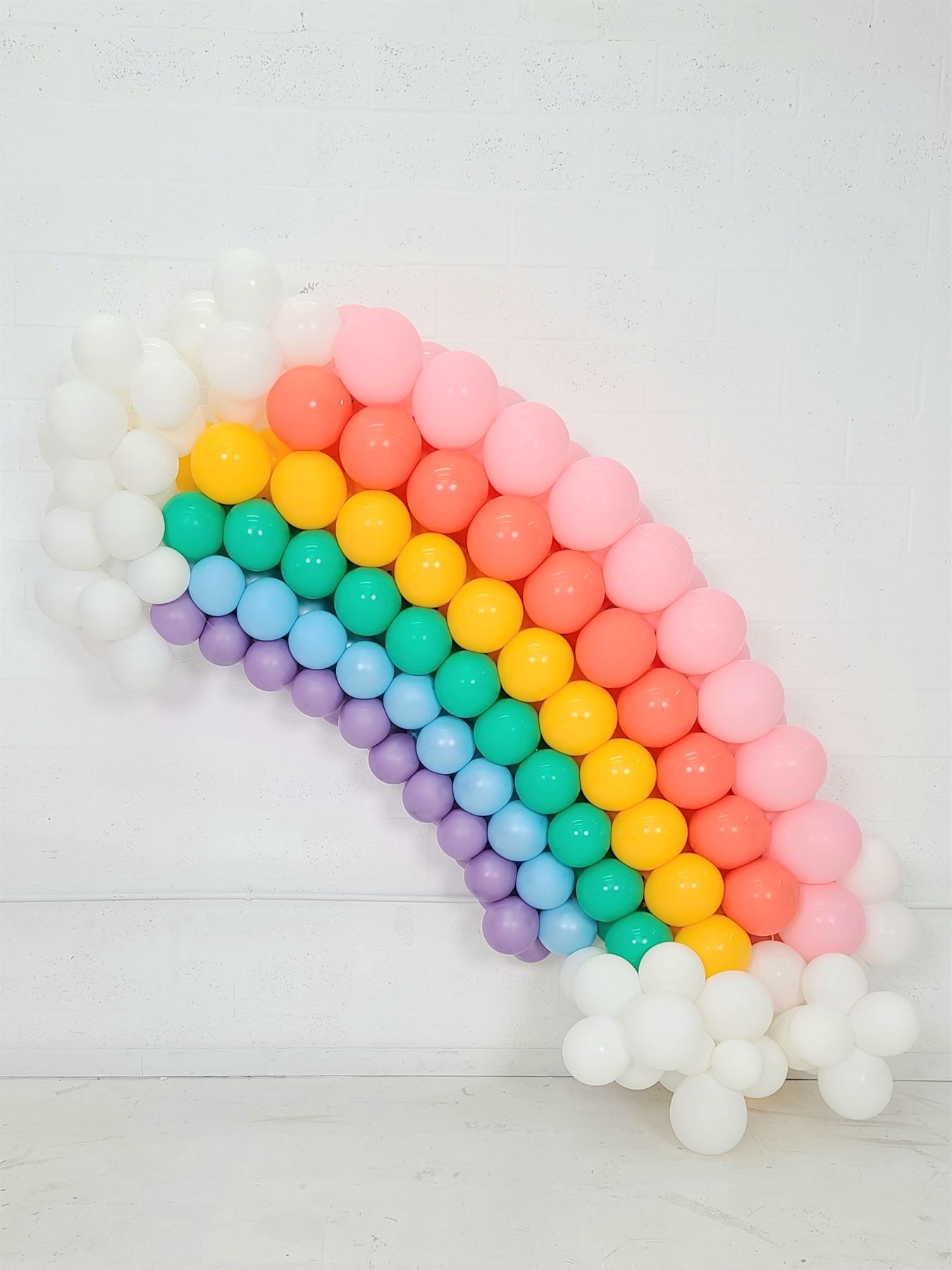 A rainbow made of balloons is sitting on a table.