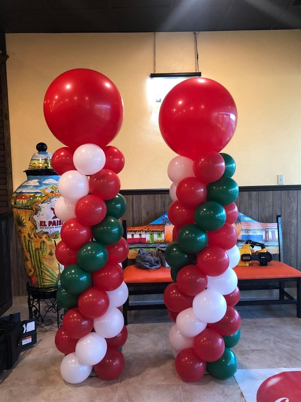 Two columns of red white and green balloons in a room.