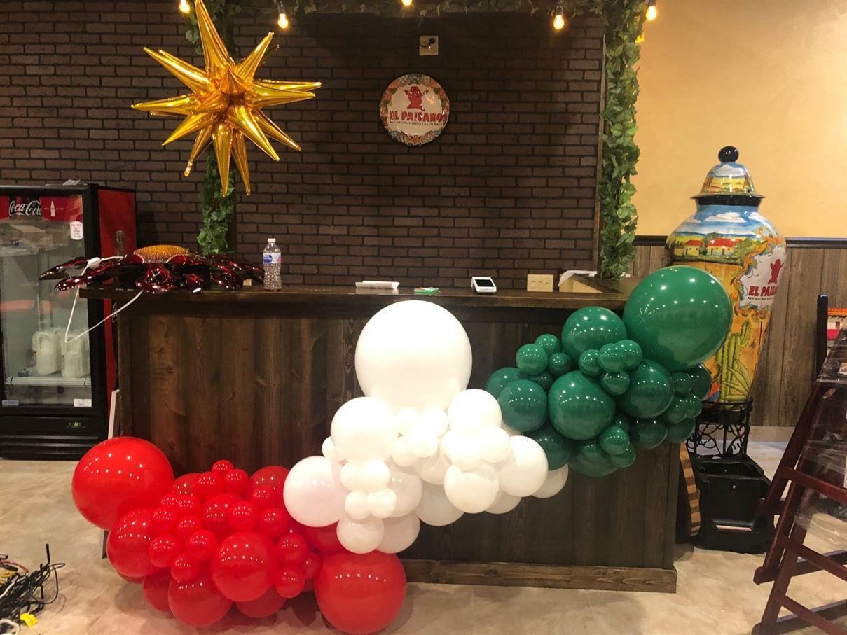 A reception desk decorated with red , white and green balloons.