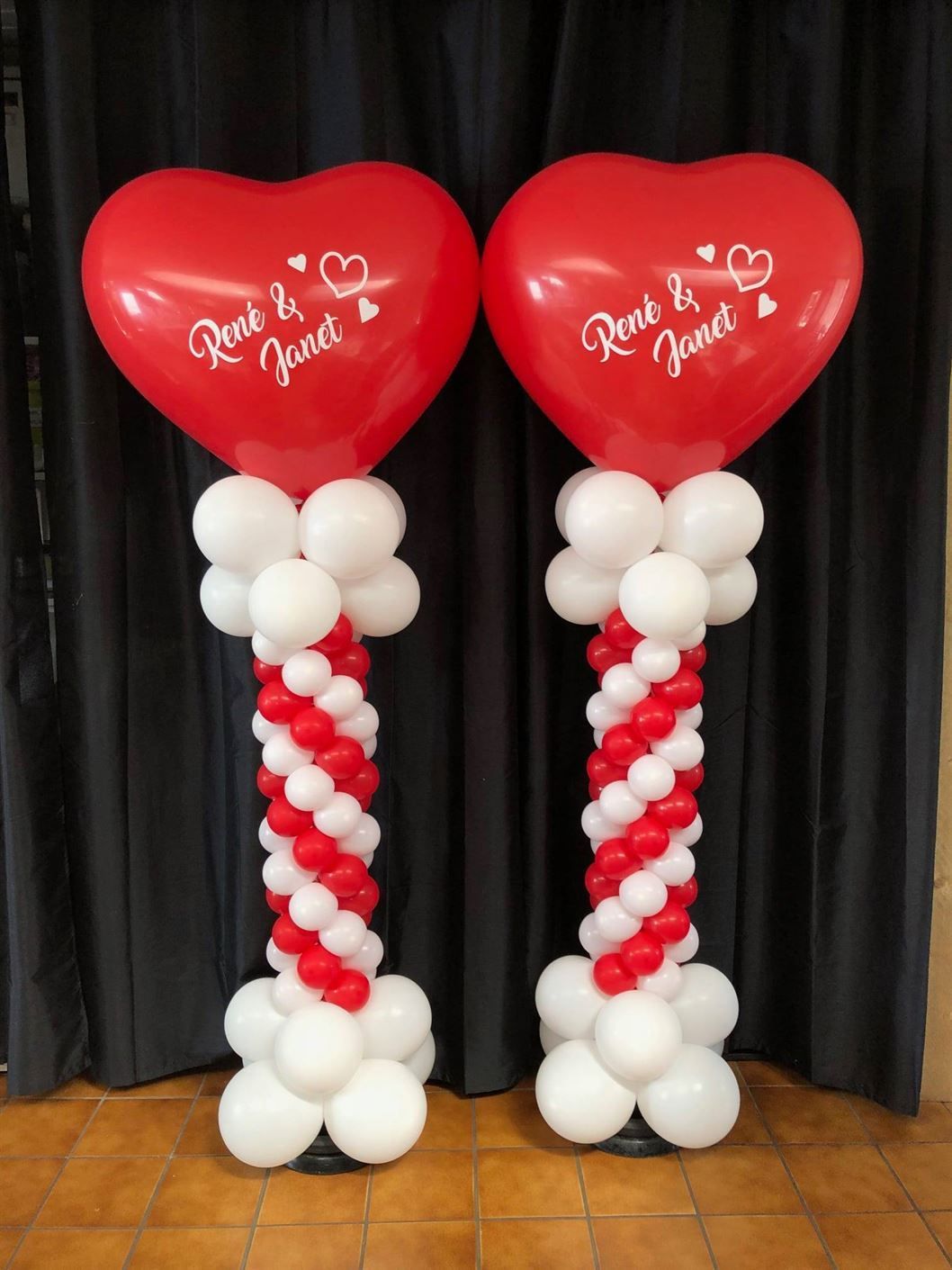 Two red and white heart shaped balloons with the names renee and janet on them