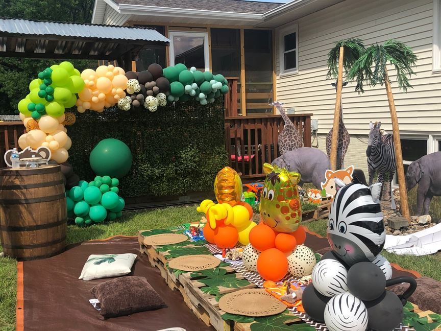A table with balloons and animals on it in front of a house.