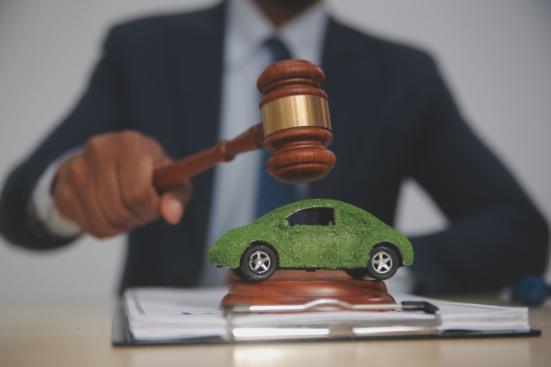 A lawyer wielding a gavel above a toy car, illustrating the legal aspects of a car accident lawyer.