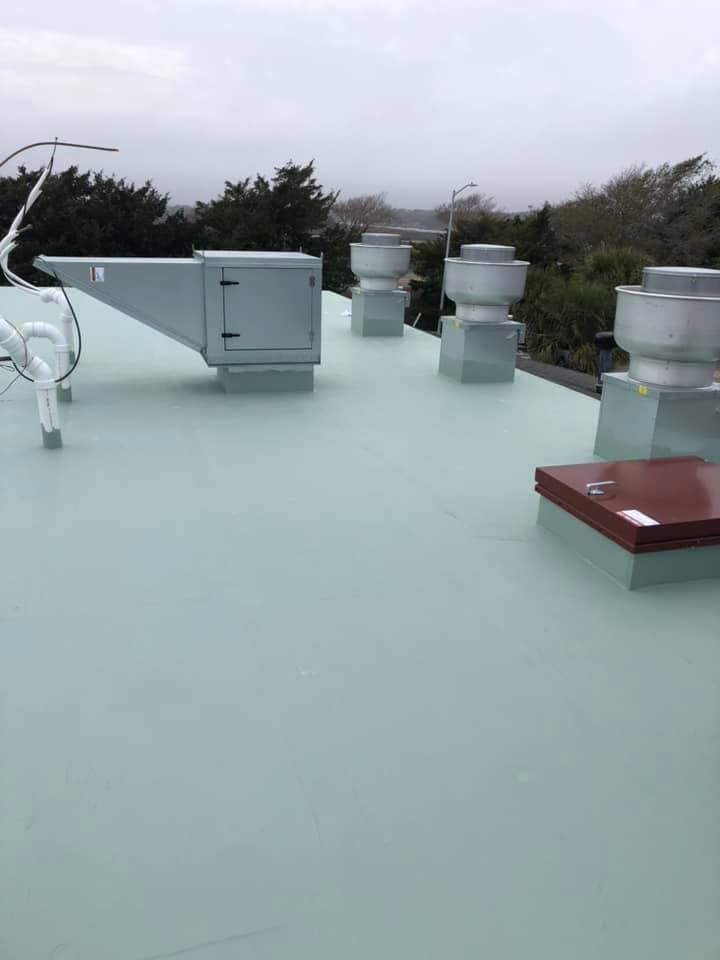 Rooftop with pale green surface, gray vents, and a red box under an overcast sky
