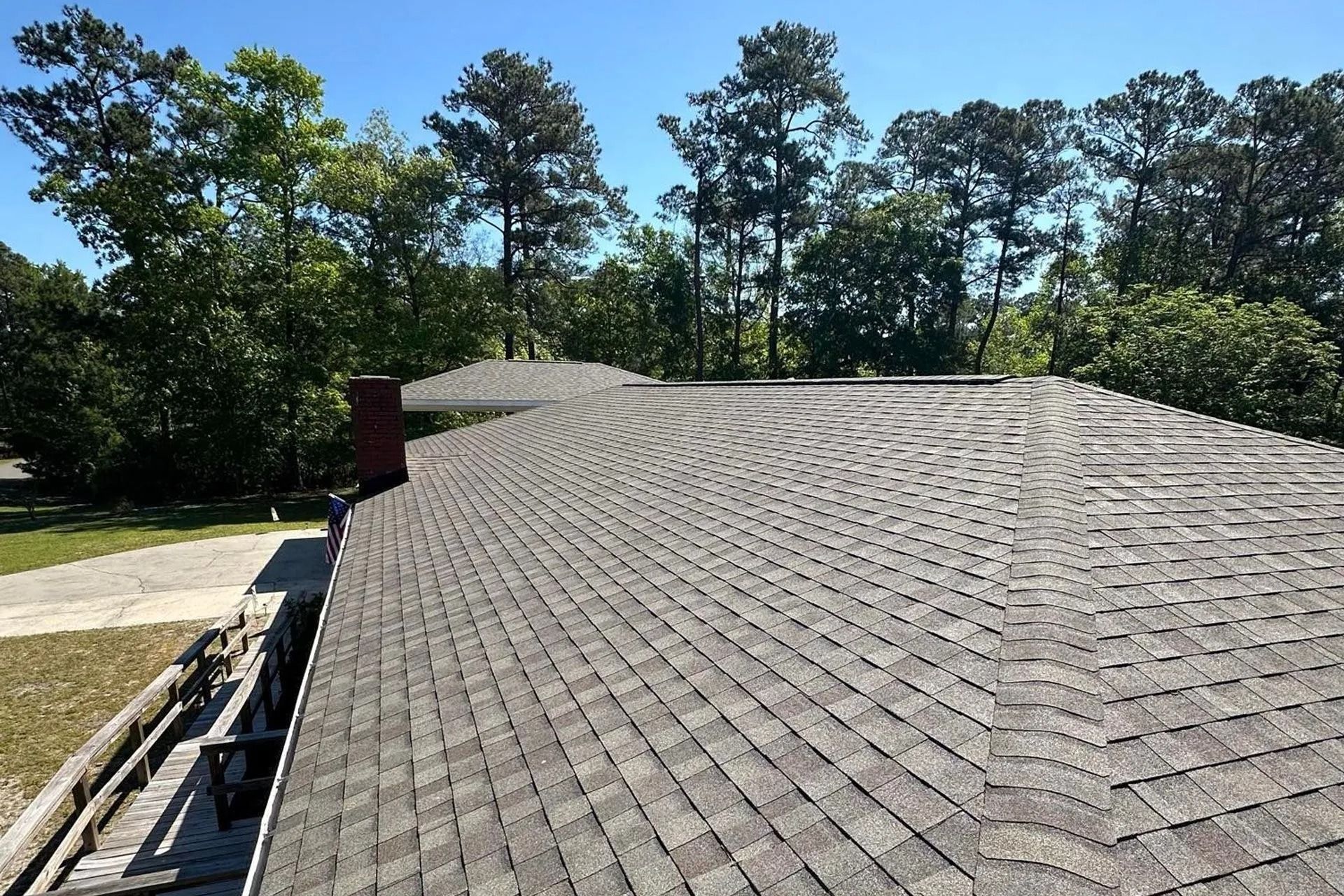Shingled roof under repair with trees in the background on a sunny day
