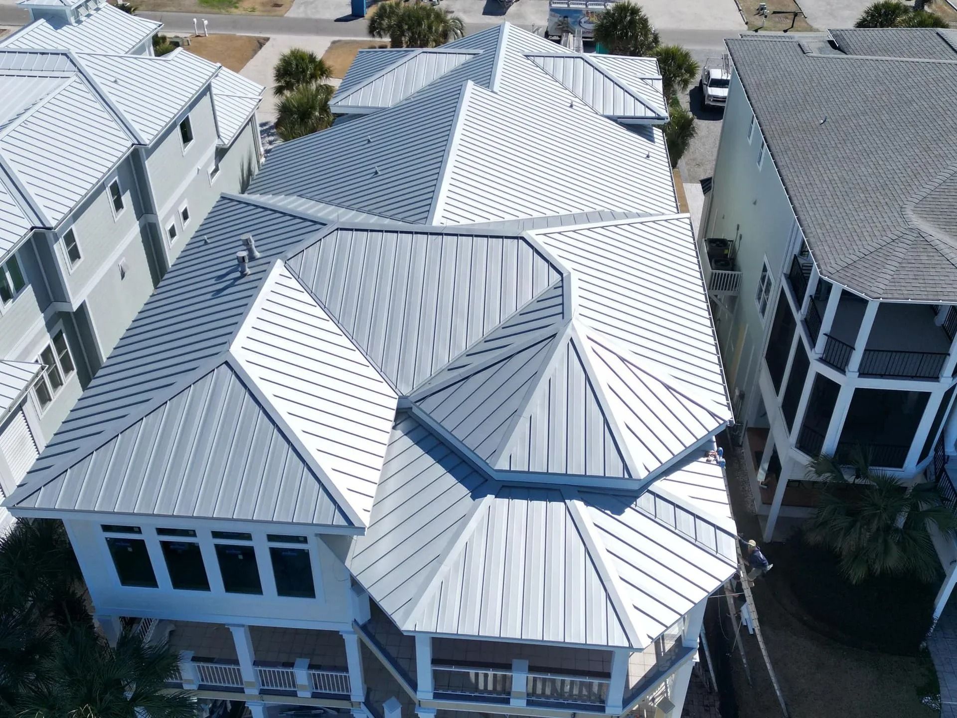 Aerial view of white-roofed waterfront homes with balconies and a canal between buildings