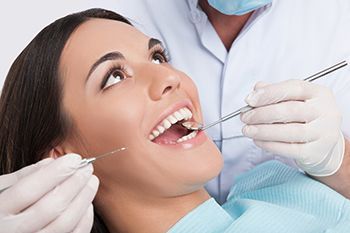 A woman is getting her teeth examined by a dentist.