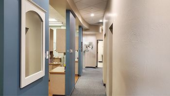 a long hallway in a dental office with a mirror on the wall .