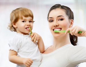 a woman and a child are brushing their teeth together .