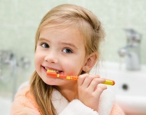 a little girl is brushing her teeth in the bathroom .