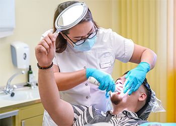 a female dentist is examining a man 's teeth in a dental office .