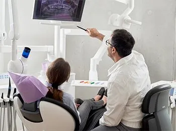 A dentist is talking to a patient in a dental chair.