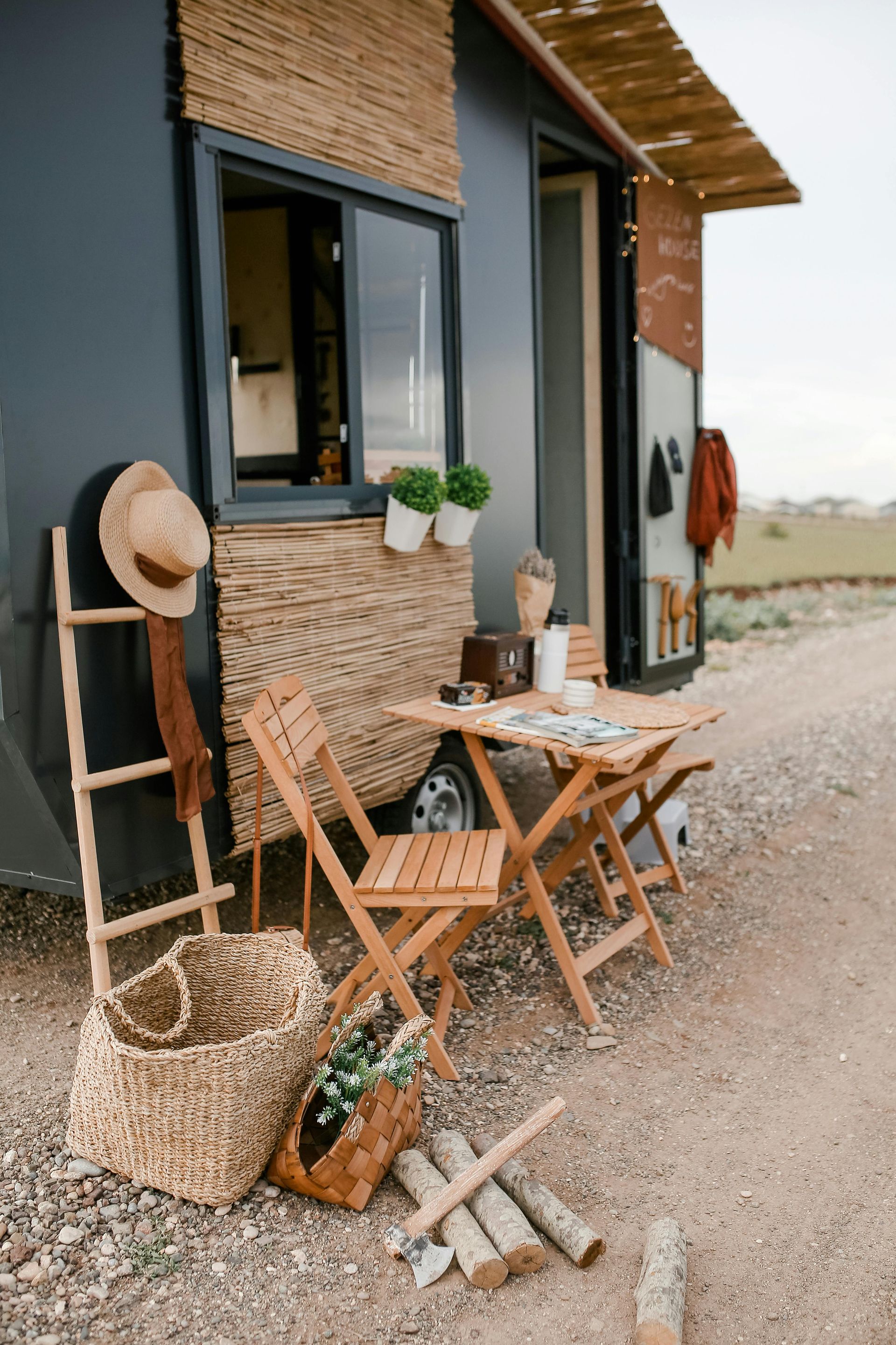 A small mobile house with a table and chairs outside of it.
