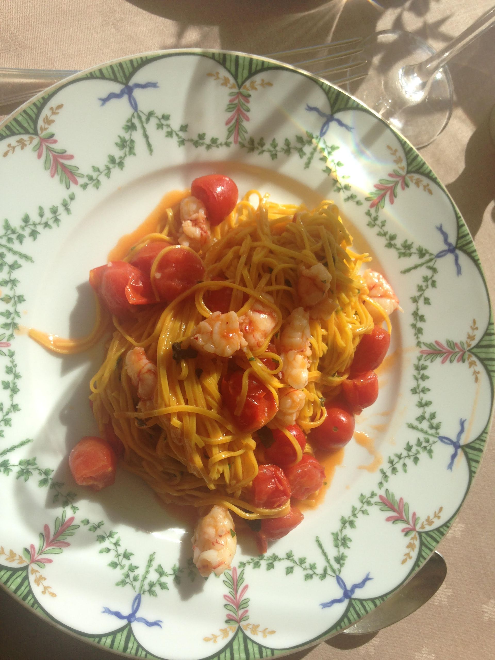 A plate of spaghetti with shrimp and tomatoes on a table