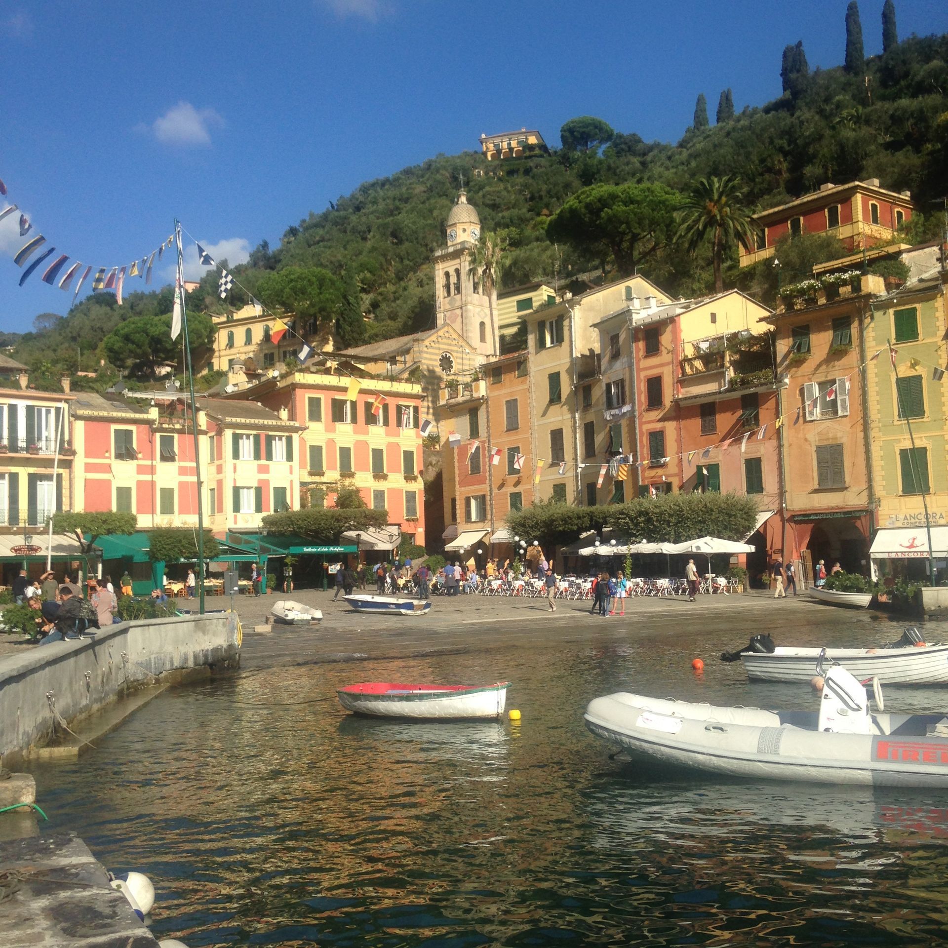 Several boats are docked in a harbor with buildings in the background