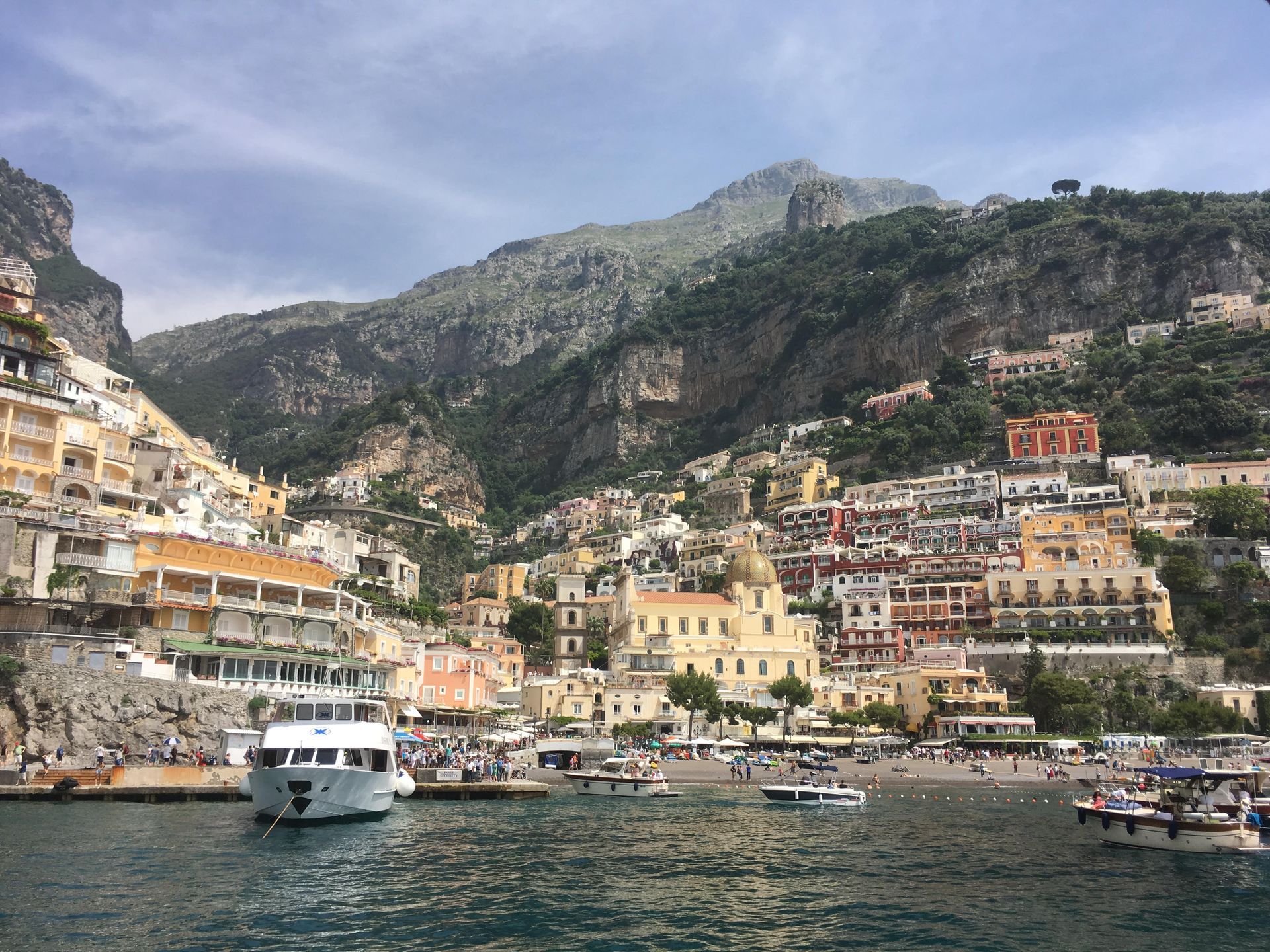 A boat is docked in front of a city with mountains in the background