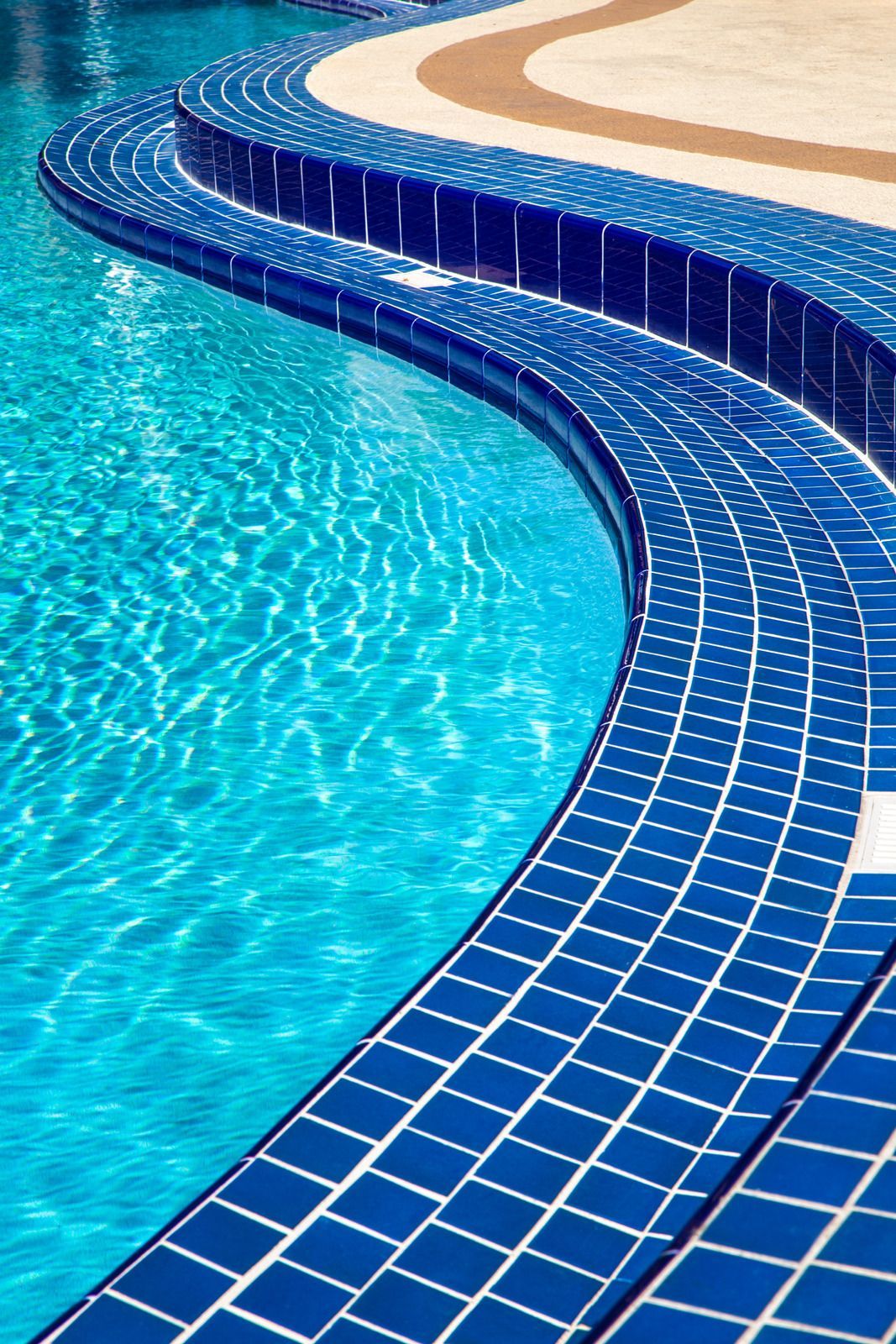 Blue tiled steps curve into a clear blue swimming pool.