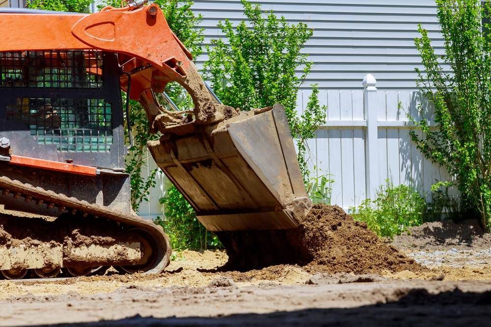 A Bulldozer is Loading Dirt Into a Bucket on a Construction Site — Downright Carpentry in Pioneer, QLD