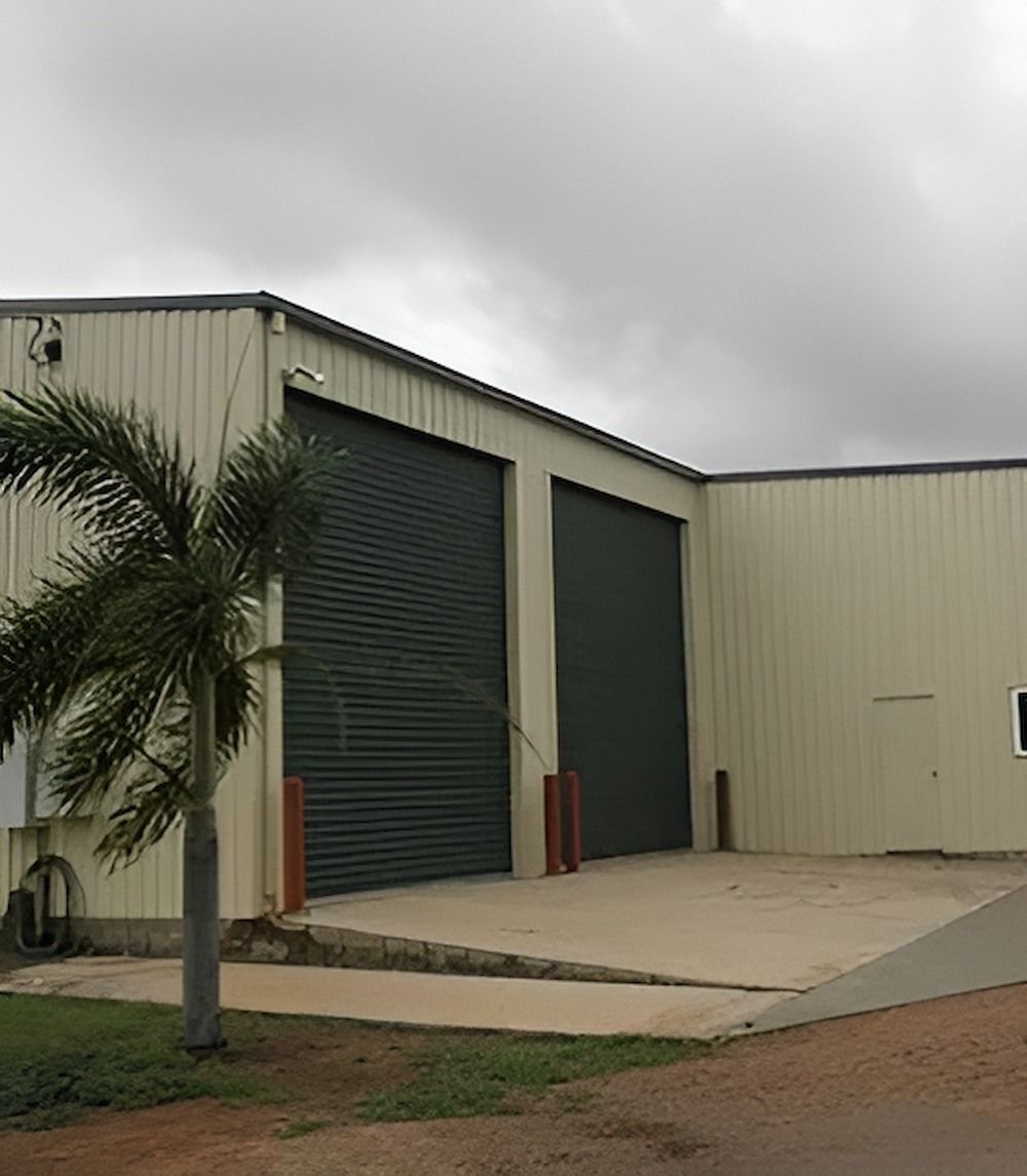 Large Building With a Lot of Garage Doors and a Palm Tree in Front of It — Downright Carpentry in Ryan, QLD
