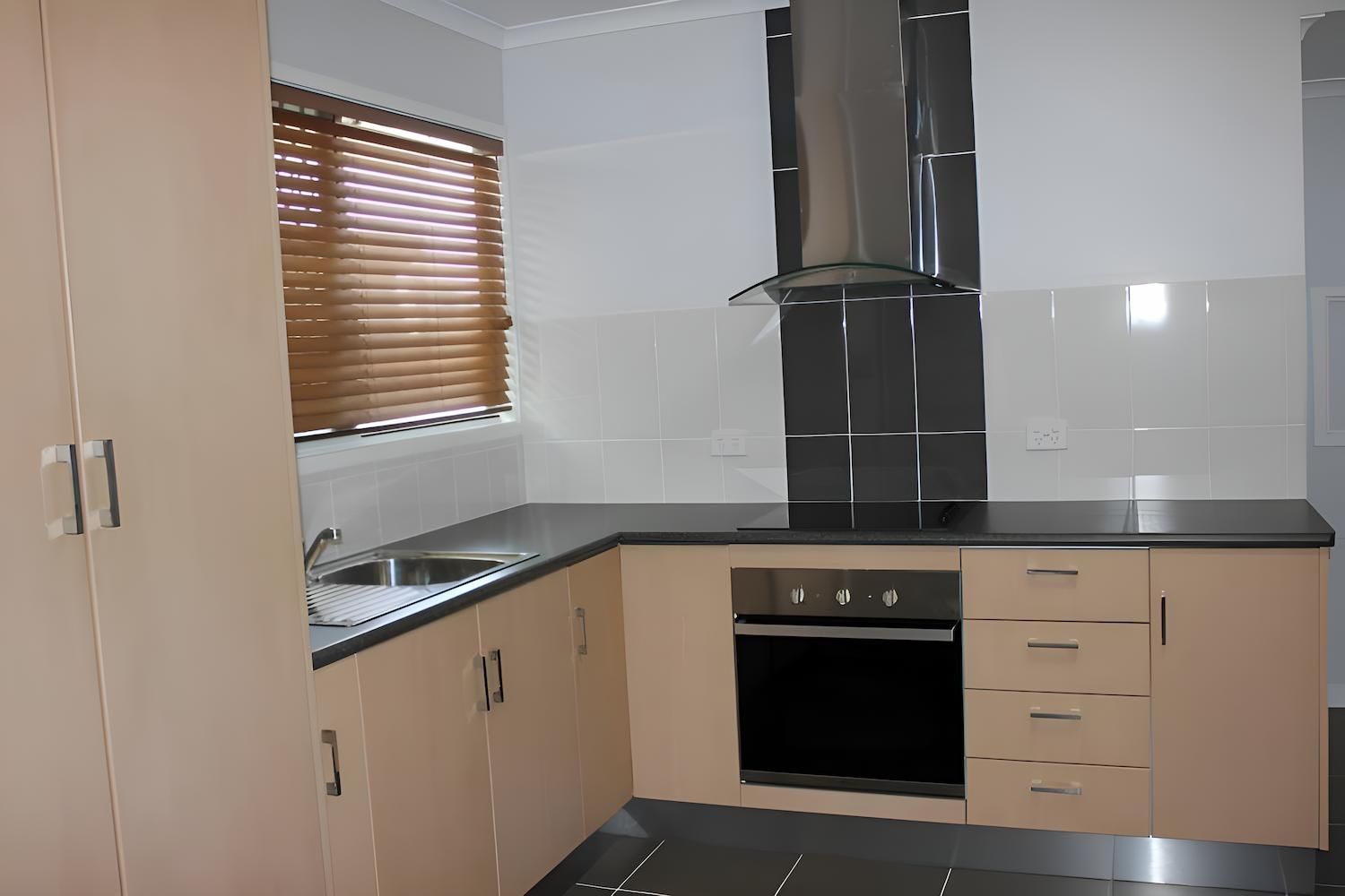 An Empty Kitchen With a Sink and Stove Top Oven — Downright Carpentry in Miles End, QLD
