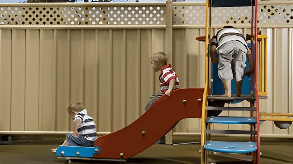 Three Children Are Playing on a Slide at a Playground — Downright Carpentry in Ryan, QLD
