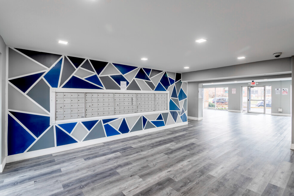 The Swift and Current Apartments lobby with grey flooring and blue and grey patterned wall paper and view of indoor mailboxes.