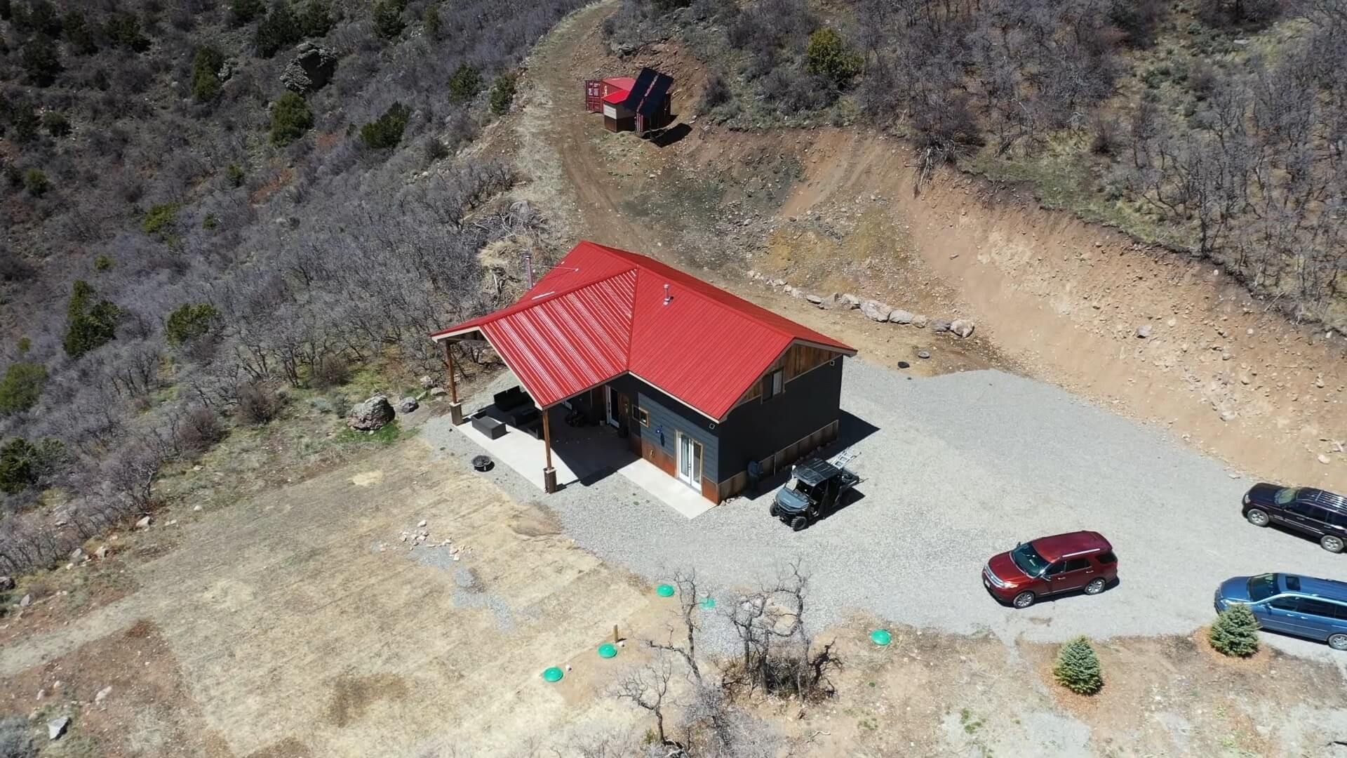 An aerial view of a house with a red roof and cars parked in front of it. Maven Construction, Montrose, CO