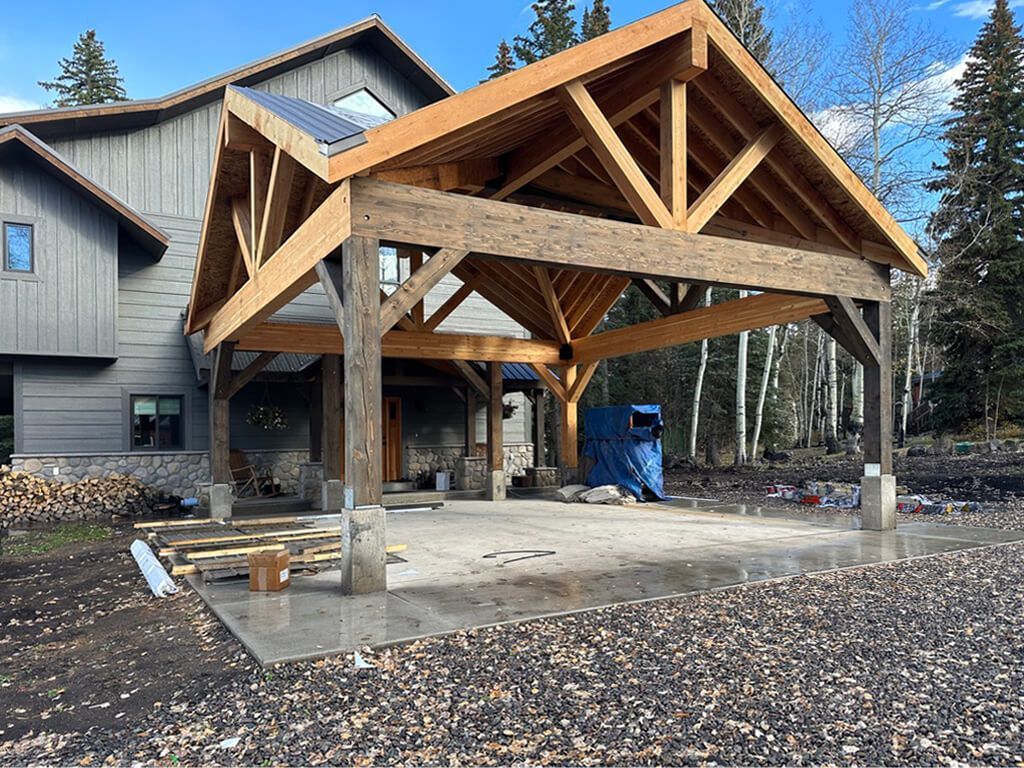 A large house with a wooden roof is being built. Maven Construction, Montrose, CO