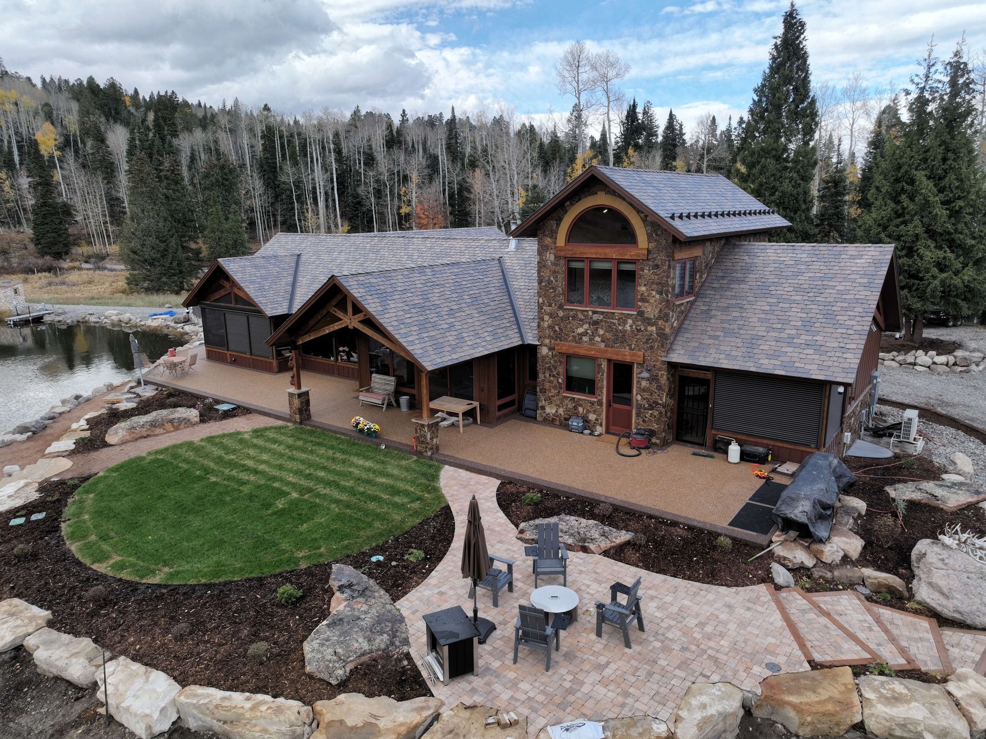 An aerial view of a large house surrounded by trees and a lake. Maven Construction, Montrose, CO