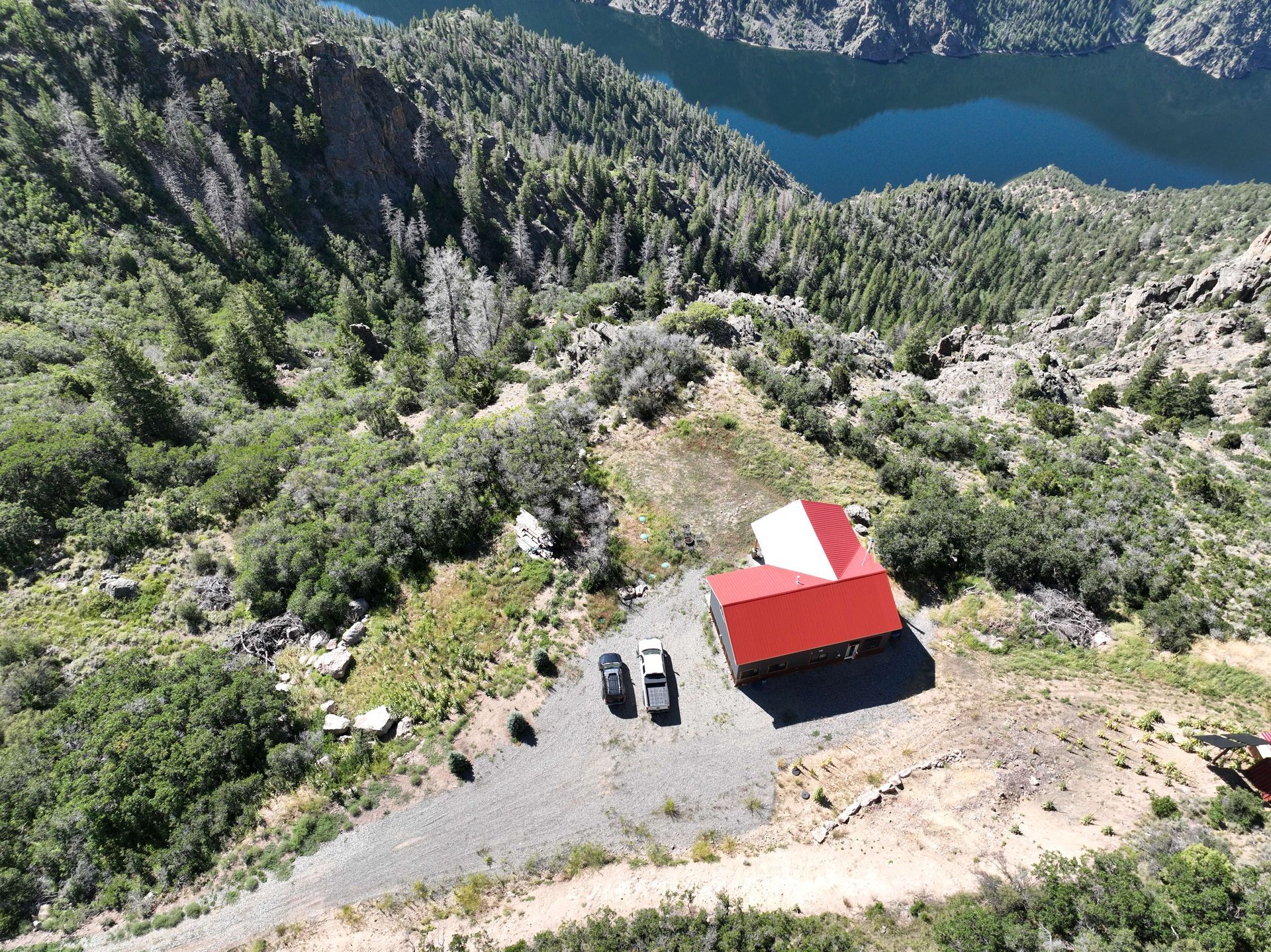 An aerial view of a red and white house on top of a hill near a lake Maven Construction, Montrose, CO