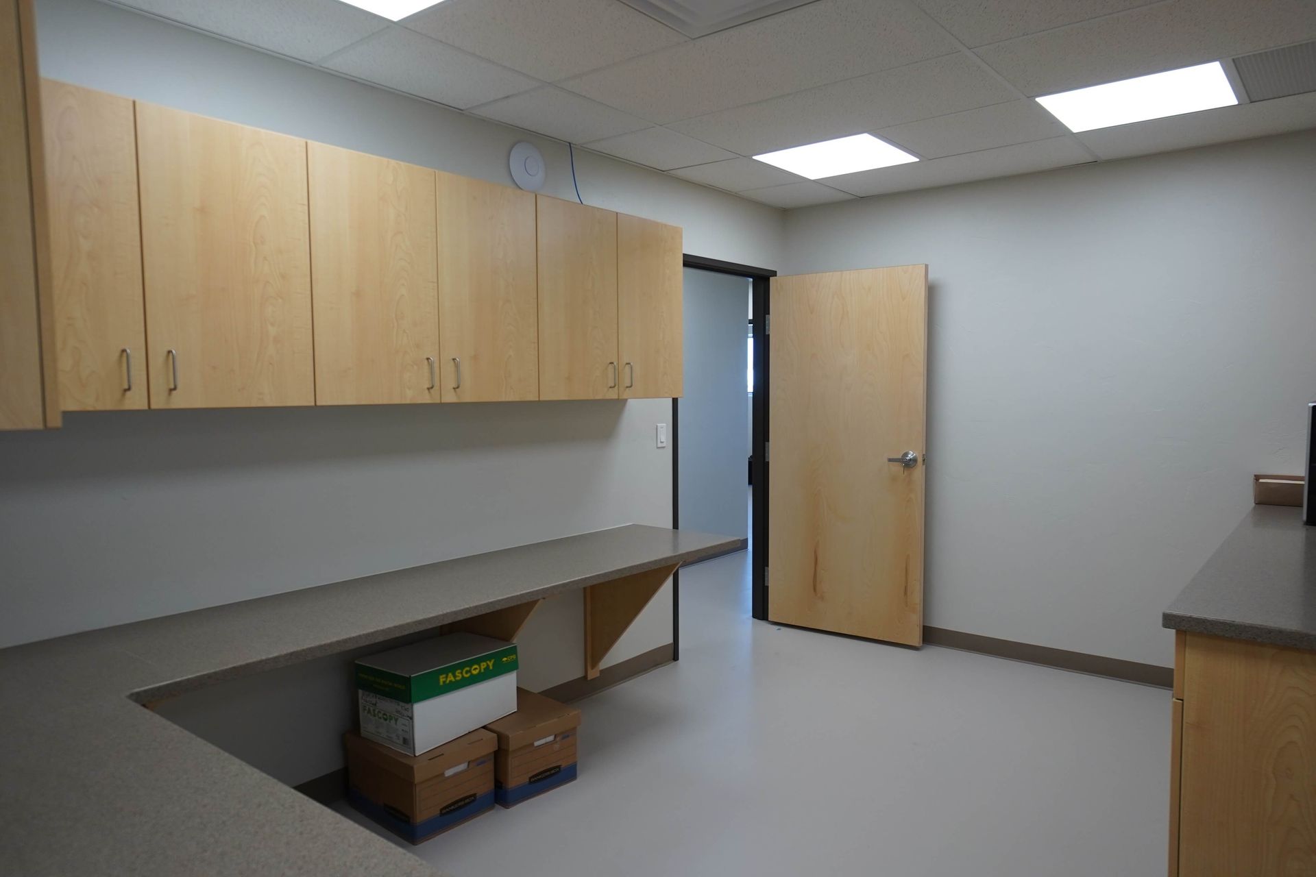 An empty room with a desk , cabinets , and a door. Maven Construction, Montrose, CO