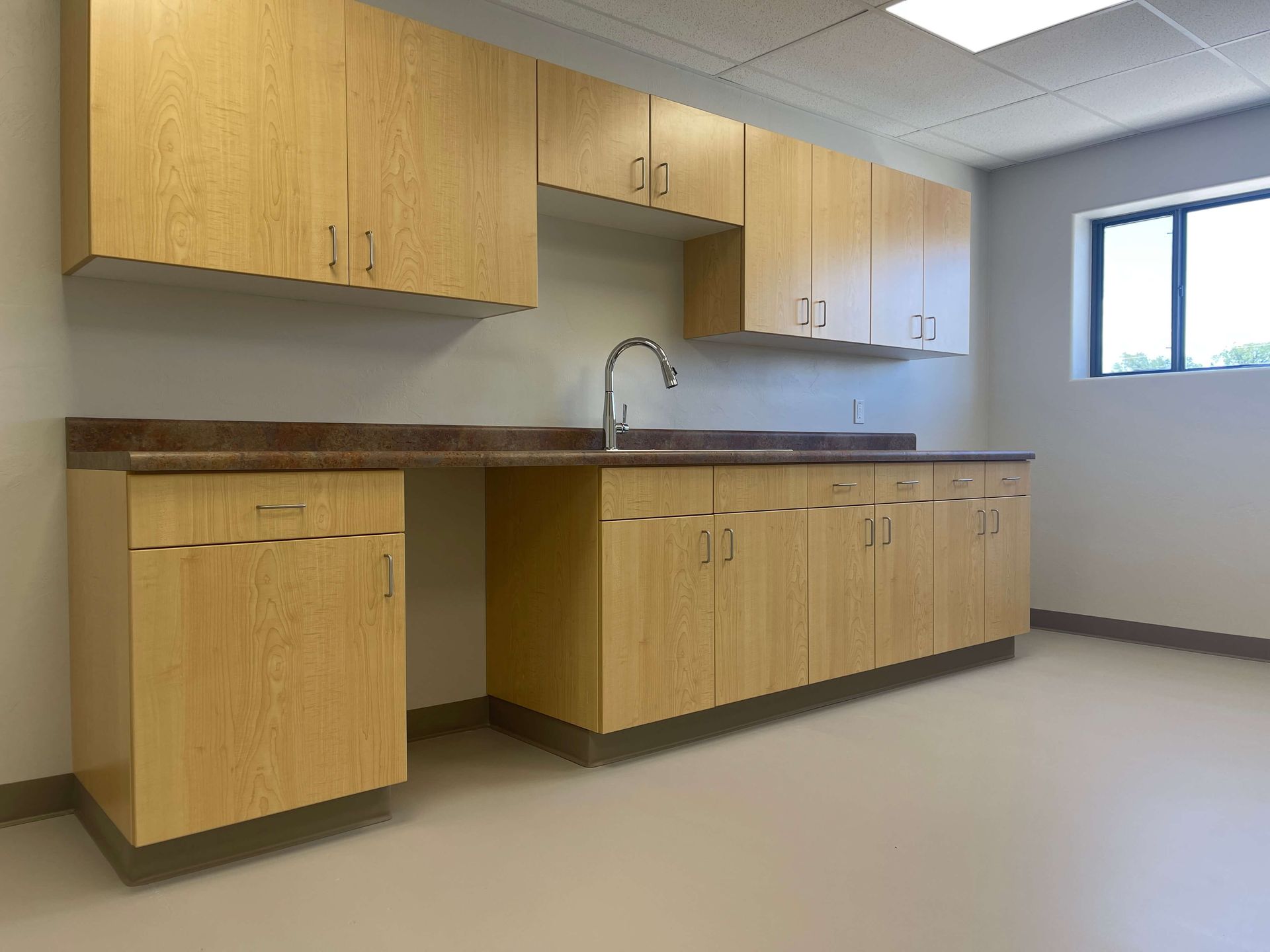 An empty kitchen with wooden cabinets and a sink. Maven Construction, Montrose, CO