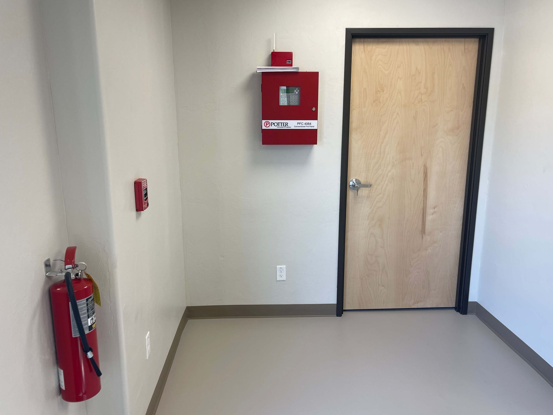 A fire extinguisher is hanging on the wall next to a door. Maven Construction, Montrose, CO