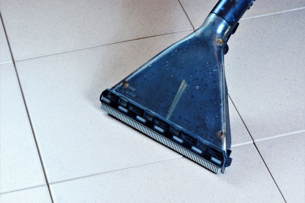 Cleaning head of a tile cleaner on white tiled floor.