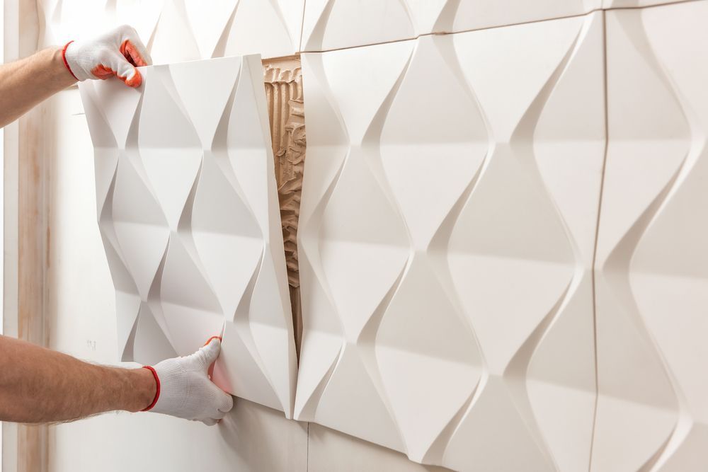 Person in gloves installing white 3D wall panels.