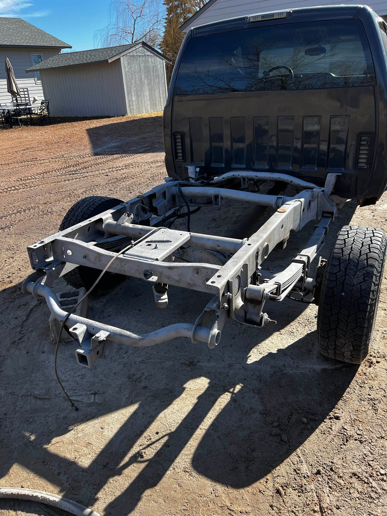 Black truck cab mounted on a gray truck frame, outdoors on a sunny day.