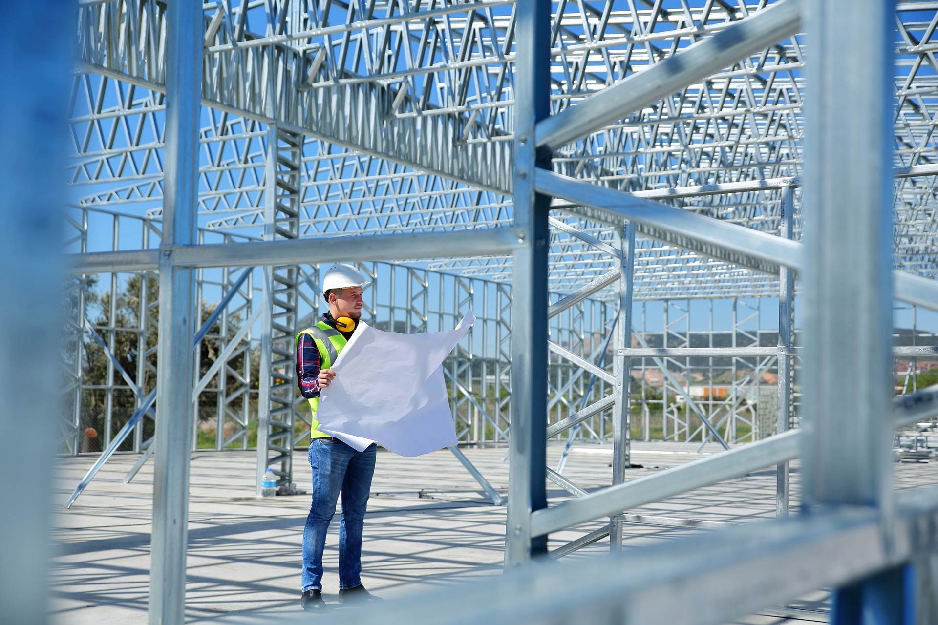 A construction worker is holding a blueprint at a construction site.