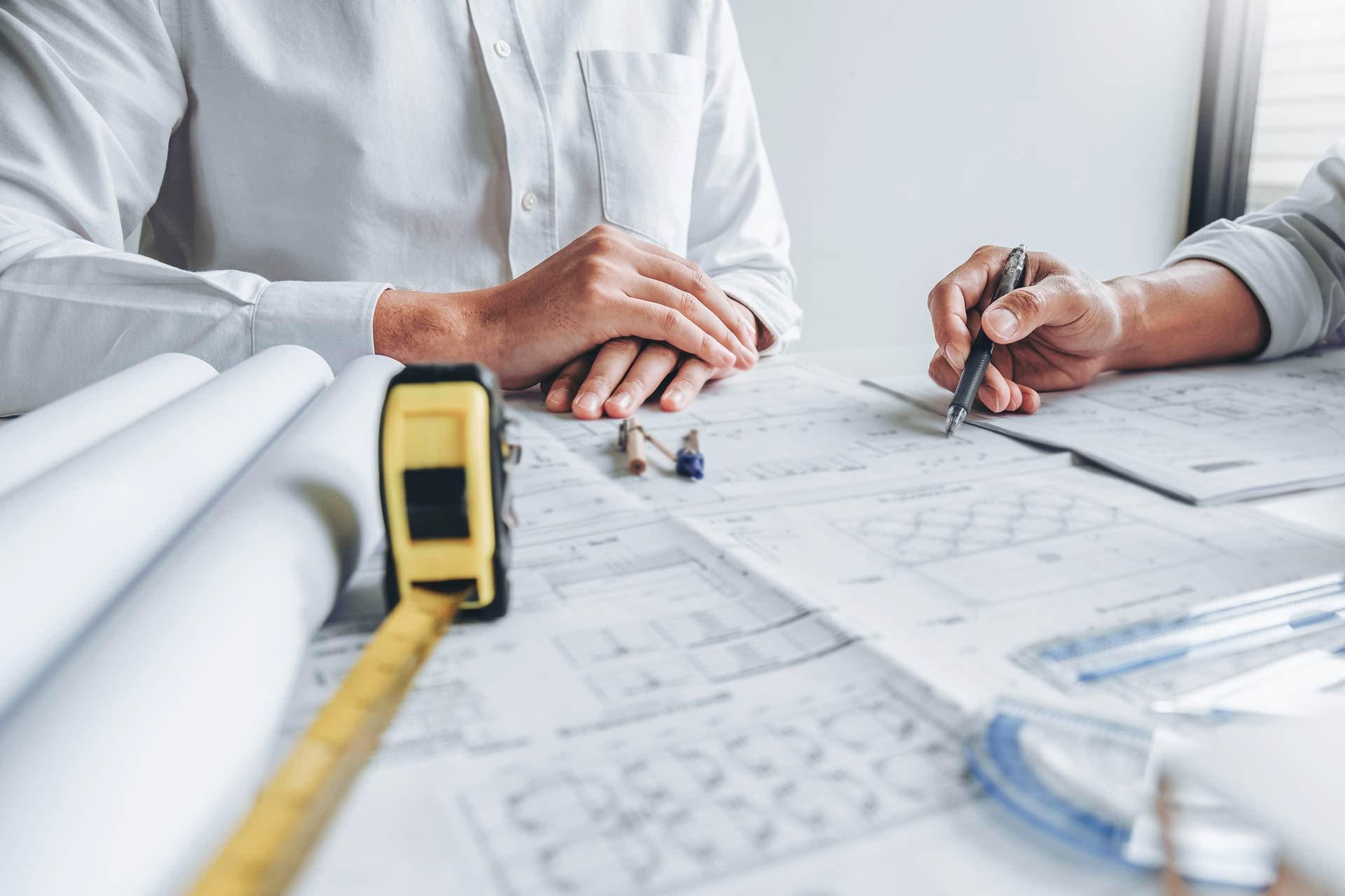 Two men are sitting at a table looking at a blueprint.